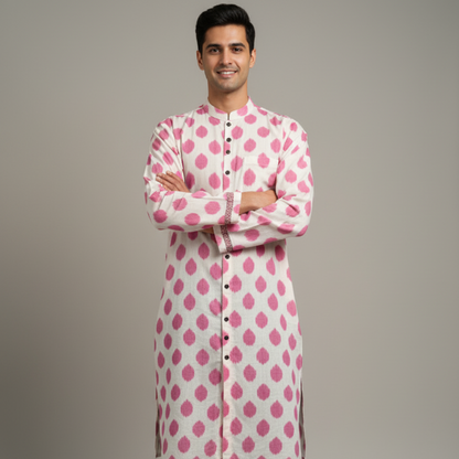 Man wearing a pink and white patterned kurta with black pants on a gray background